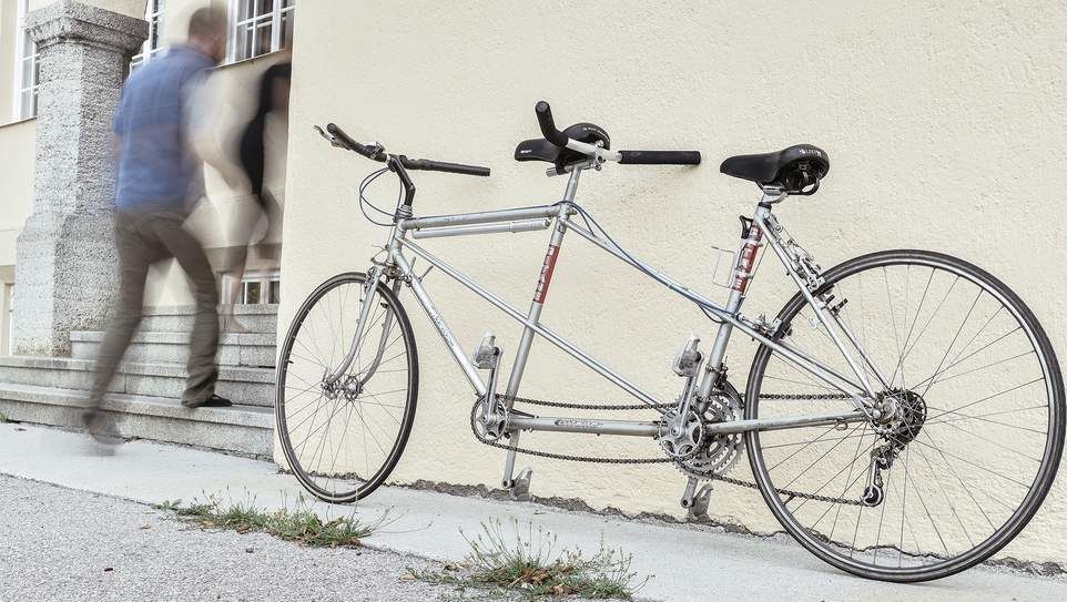 Tandemfahrrad lehnt an Schulgebäude